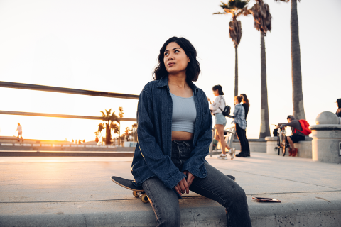 Woman sitting on a skateboard. 