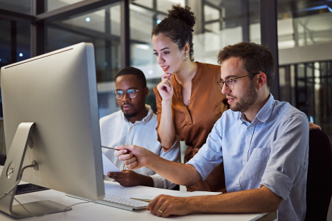 A group of three people looking at a monitor.