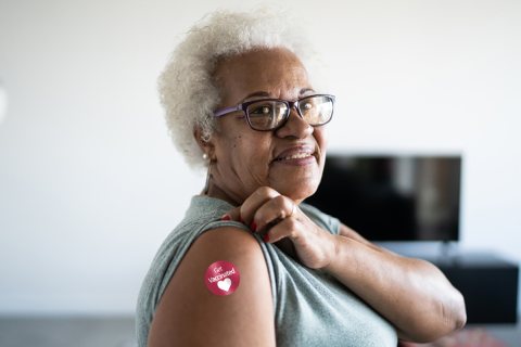 Woman rolling up her sleeve to show a sticker on her arm that says "Get Vaccinated".