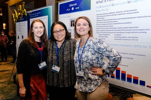 Three people standing next to each other in front of a board.